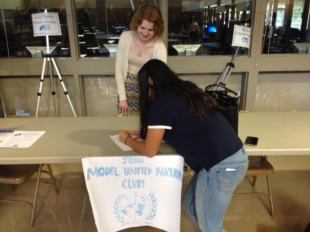 Club founder, Natalie Treichel, stands at  her booth at the club fair as sophomore Christina Shepich signs up for MUN.
Photo by: Sara Trumza