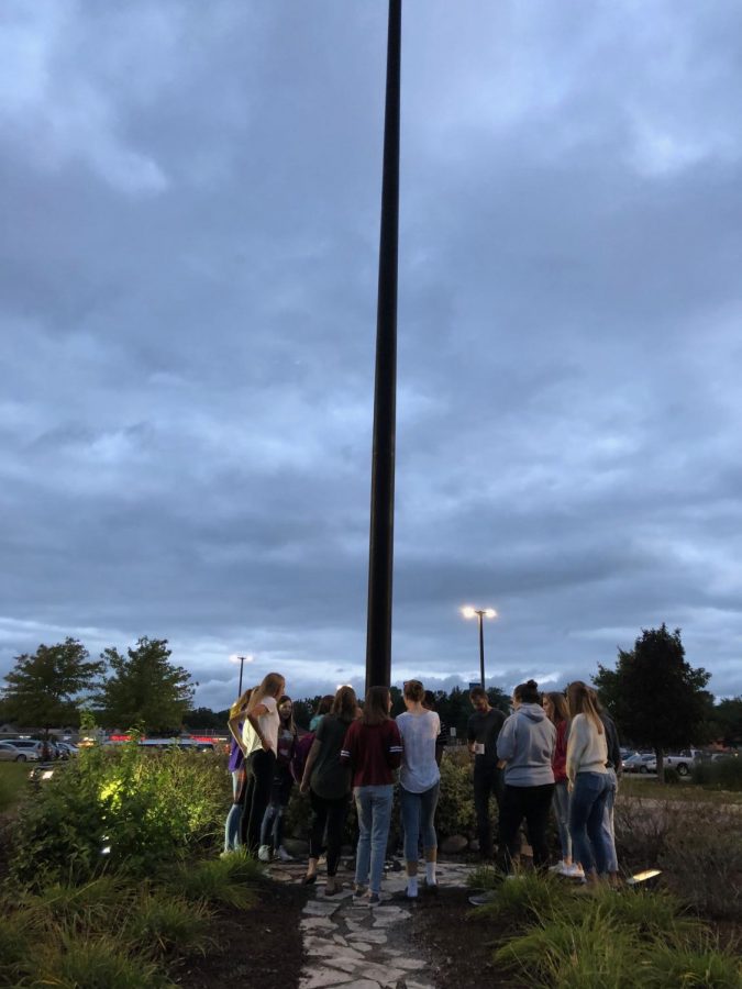 Reach members gather around the flag pole as they pray like they do towards the end of every meeting.