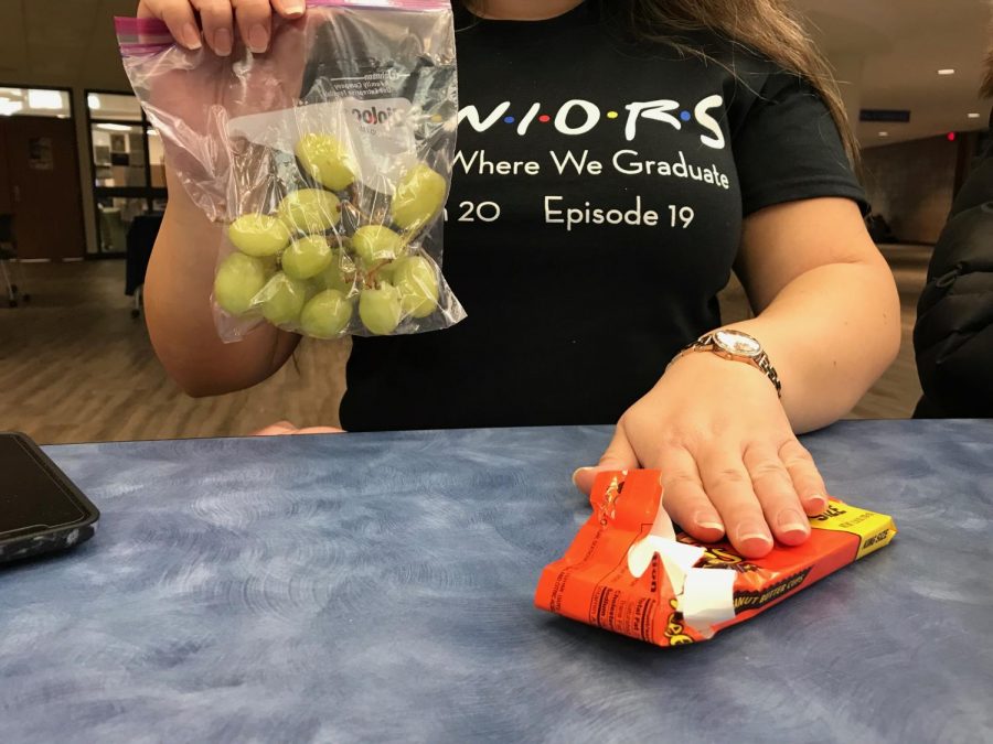 Senior Nicollette Jaye chooses grapes, a healthy fruit, over Reeses, an unhealthy candy, to maintain her New Years resolution. Photo by Alex Glaspie.